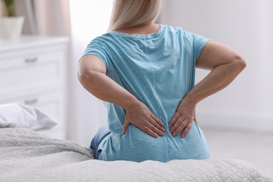 Senior woman suffering from back pain at home, closeup