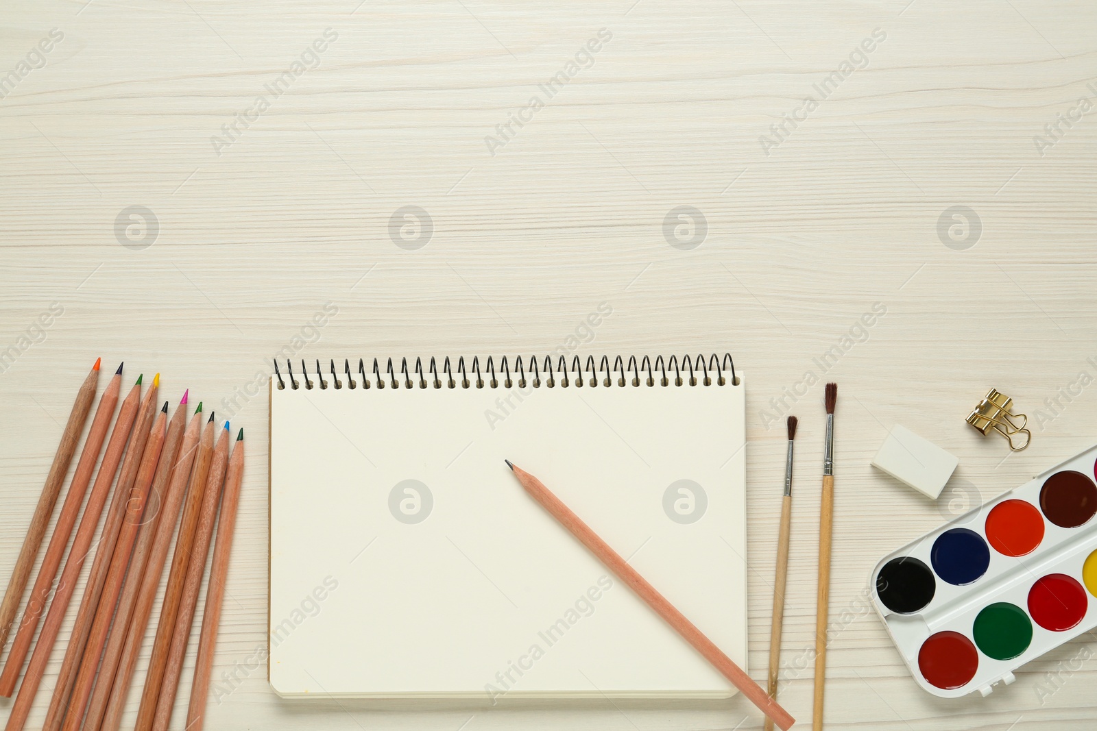 Photo of Flat lay composition with blank sketchbook on white wooden table. Space for text