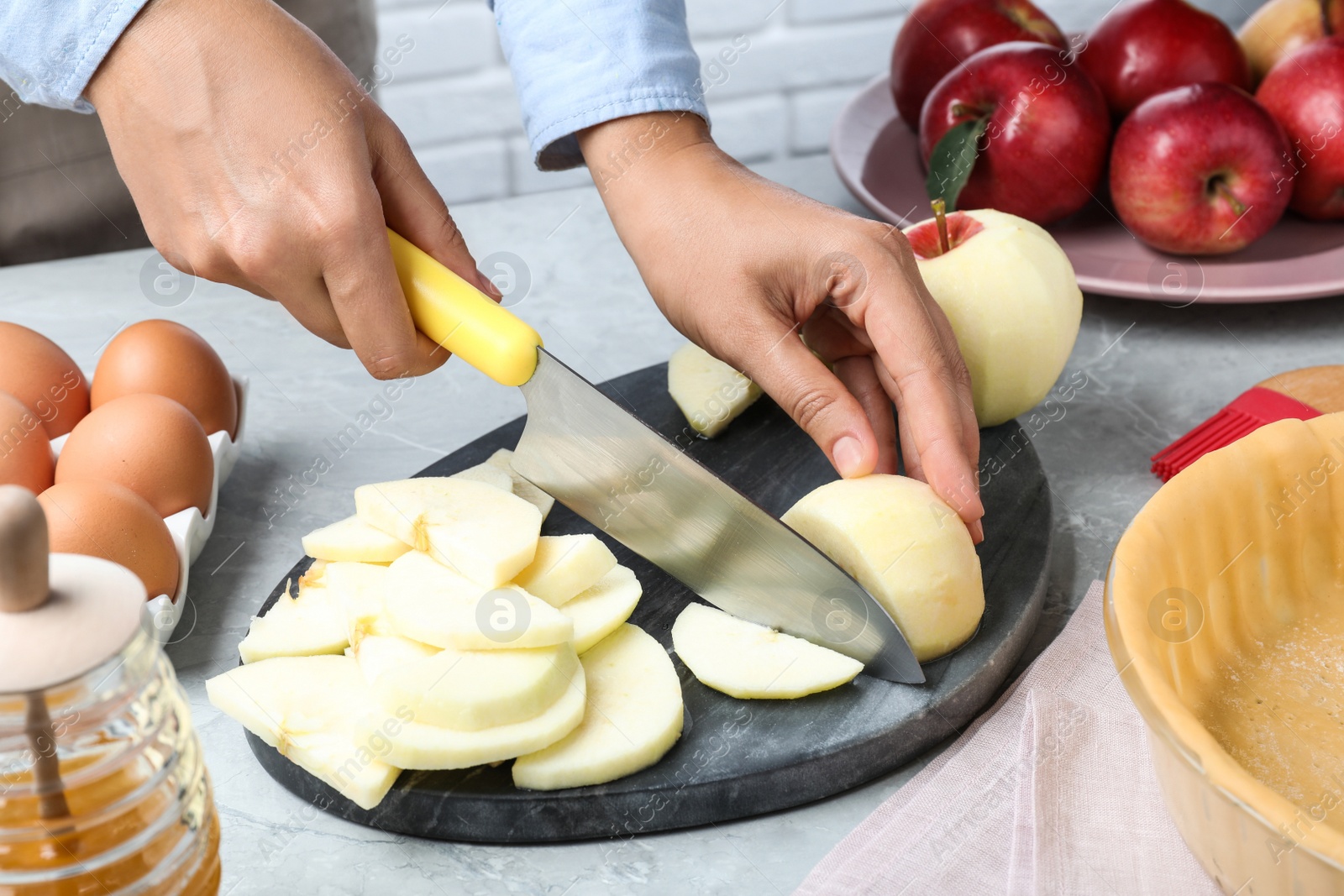 Photo of Woman cutting apple at grey table, closeup. Baking pie