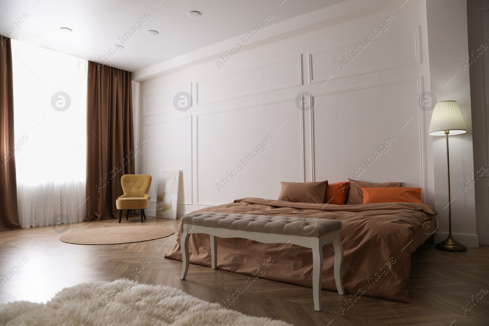 Photo of Bed with orange and brown linens in stylish room