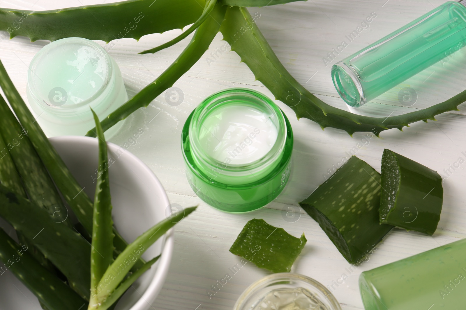Photo of Different cosmetic products and cut aloe vera leaves on white wooden table, above view
