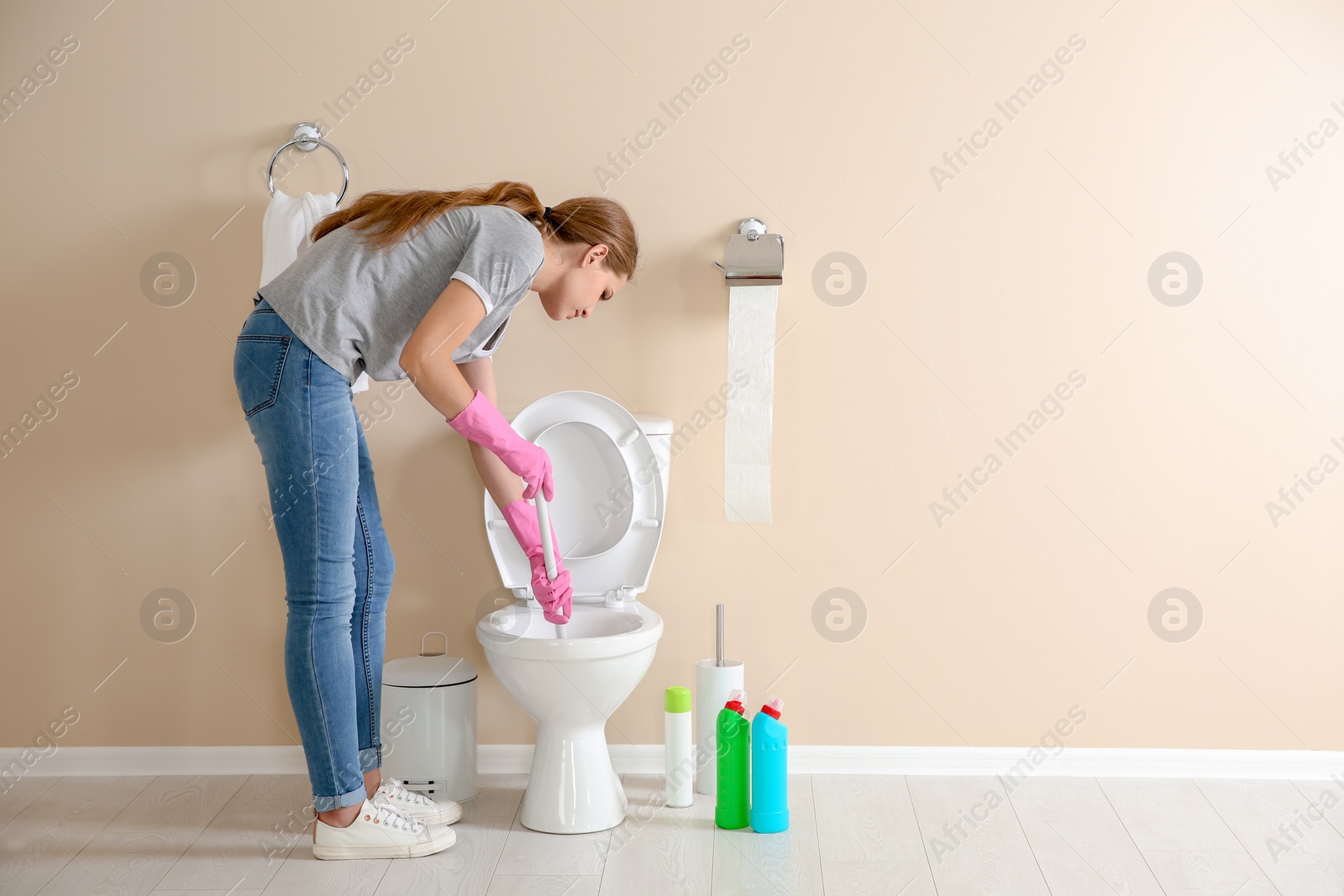 Photo of Woman cleaning toilet bowl in bathroom