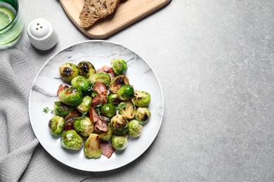 Photo of Delicious Brussels sprouts with bacon served on light table, flat lay. Space for text