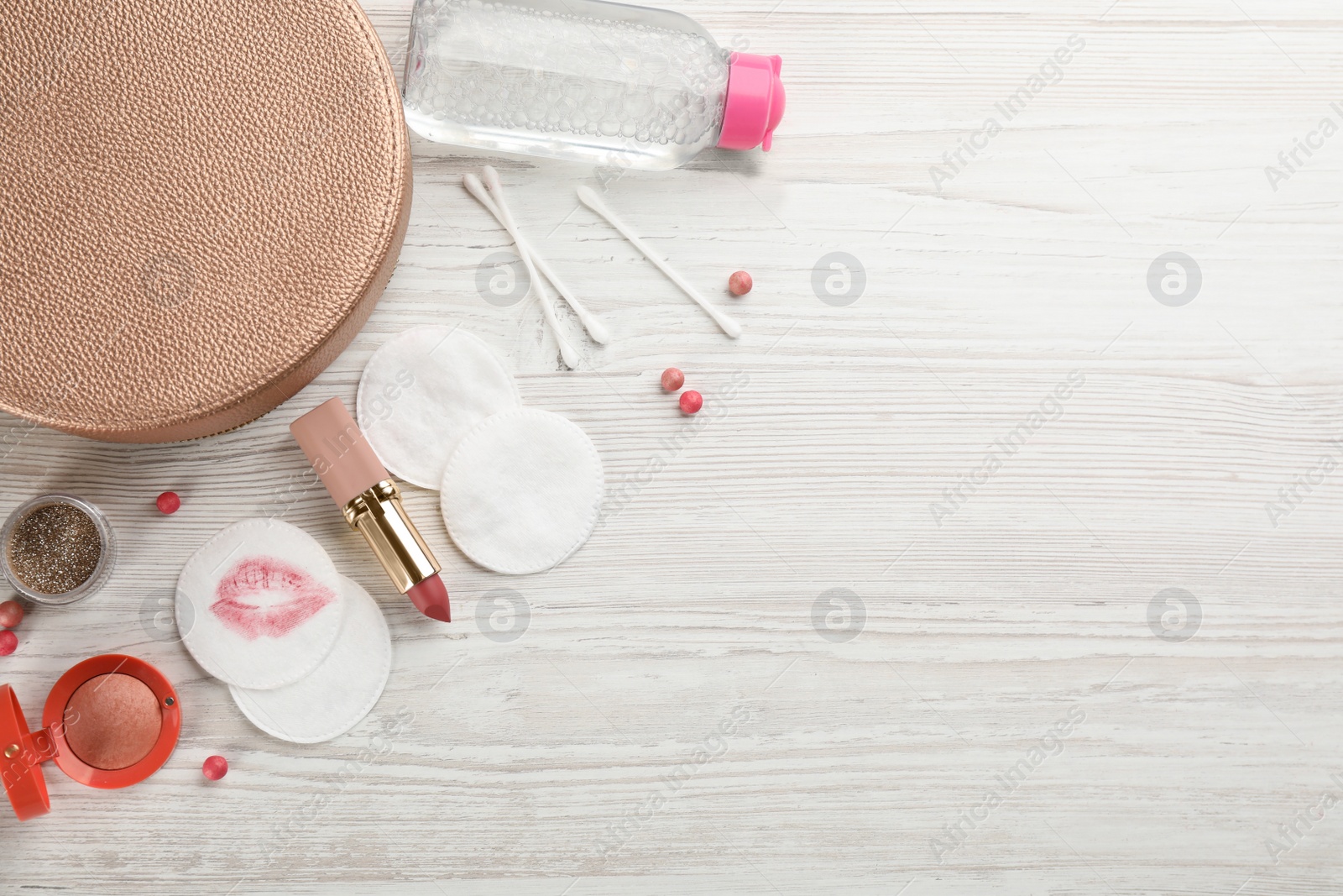 Photo of Dirty cotton pads, swabs and cosmetic products on white wooden table, flat lay. Space for text