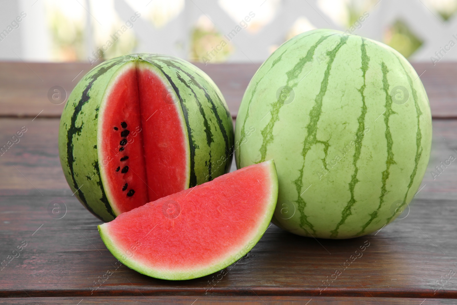 Photo of Different delicious ripe watermelons on wooden table