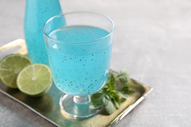 Photo of Tasty light blue drink with basil seeds on grey table