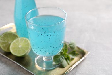 Tasty light blue drink with basil seeds on grey table