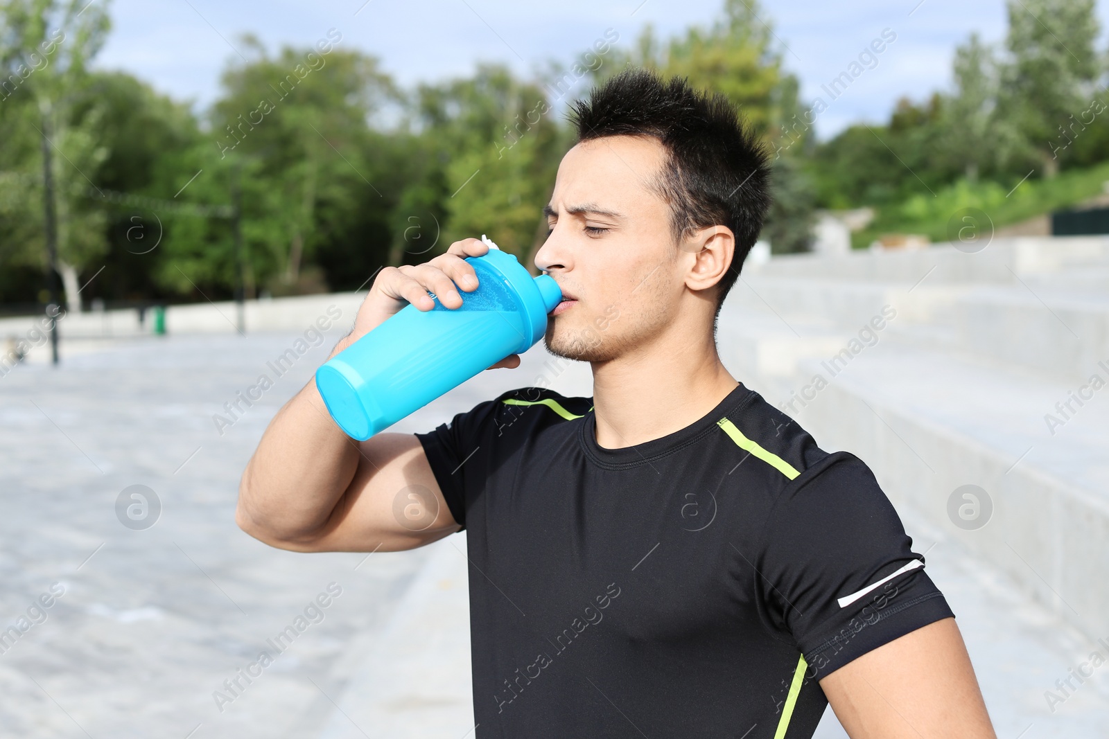 Photo of Young man drinking protein shake on street