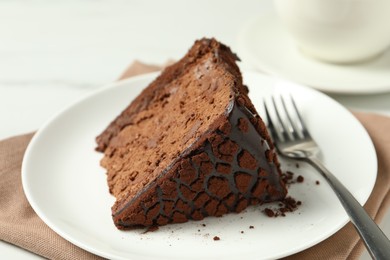 Photo of Piece of delicious chocolate truffle cake and fork on table, closeup