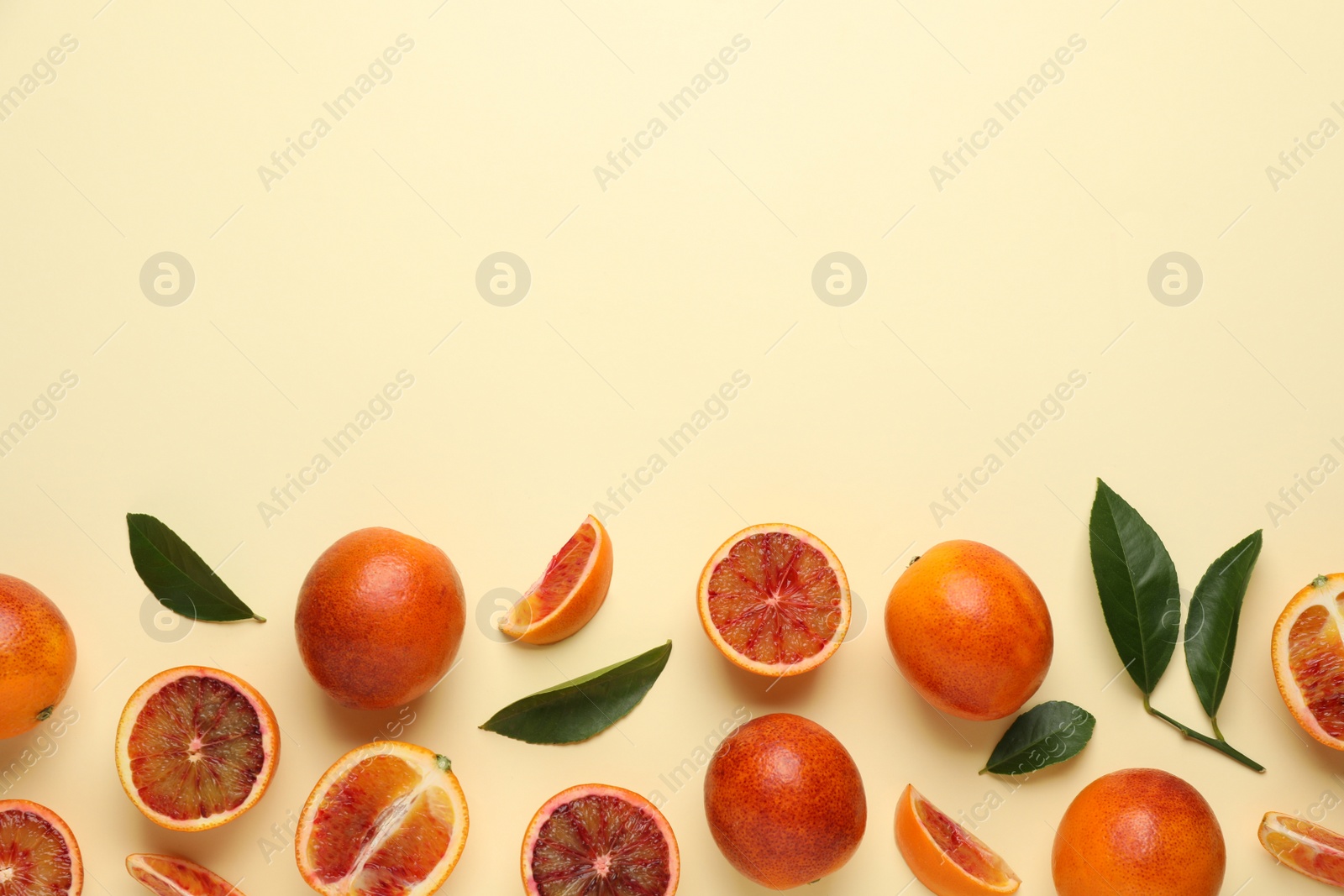 Photo of Many ripe sicilian oranges and leaves on beige background, flat lay. Space for text