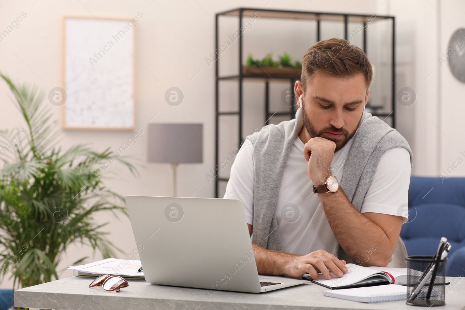 Photo of Young man with earphones working at home