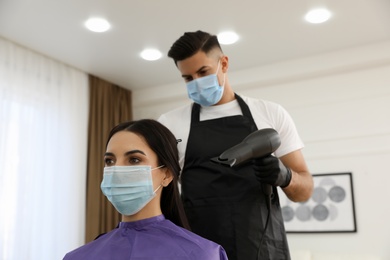 Photo of Professional stylist working with client in salon. Hairdressing services during Coronavirus quarantine