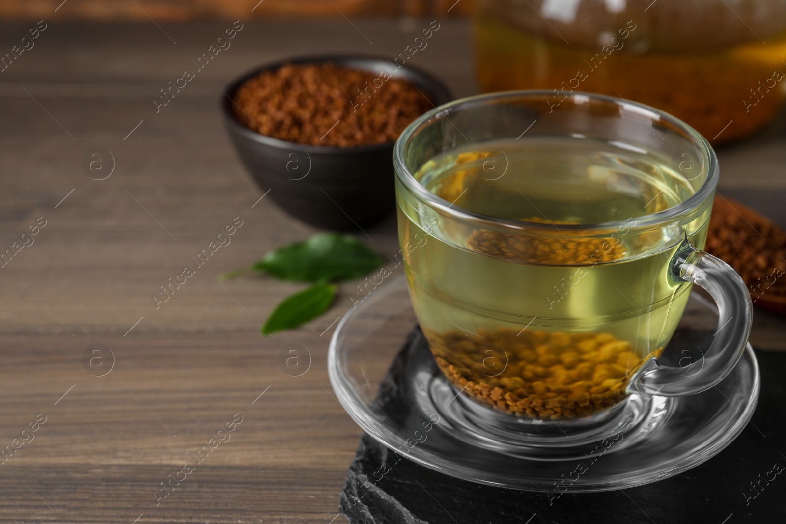 Photo of Freshly made buckwheat tea in glass cup on wooden table. Space for text