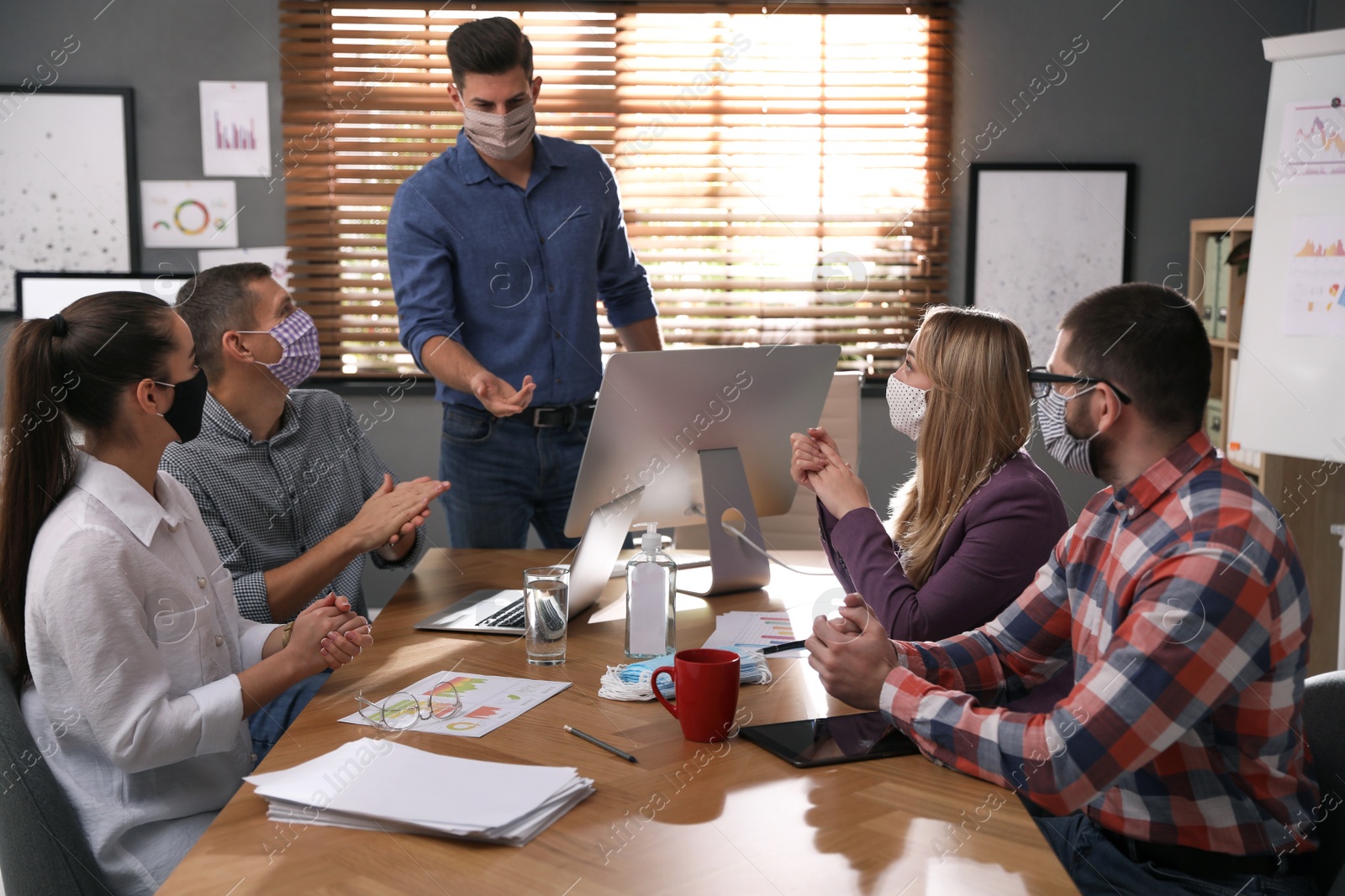 Photo of Group of coworkers with protective masks in office. Business meeting during COVID-19 pandemic