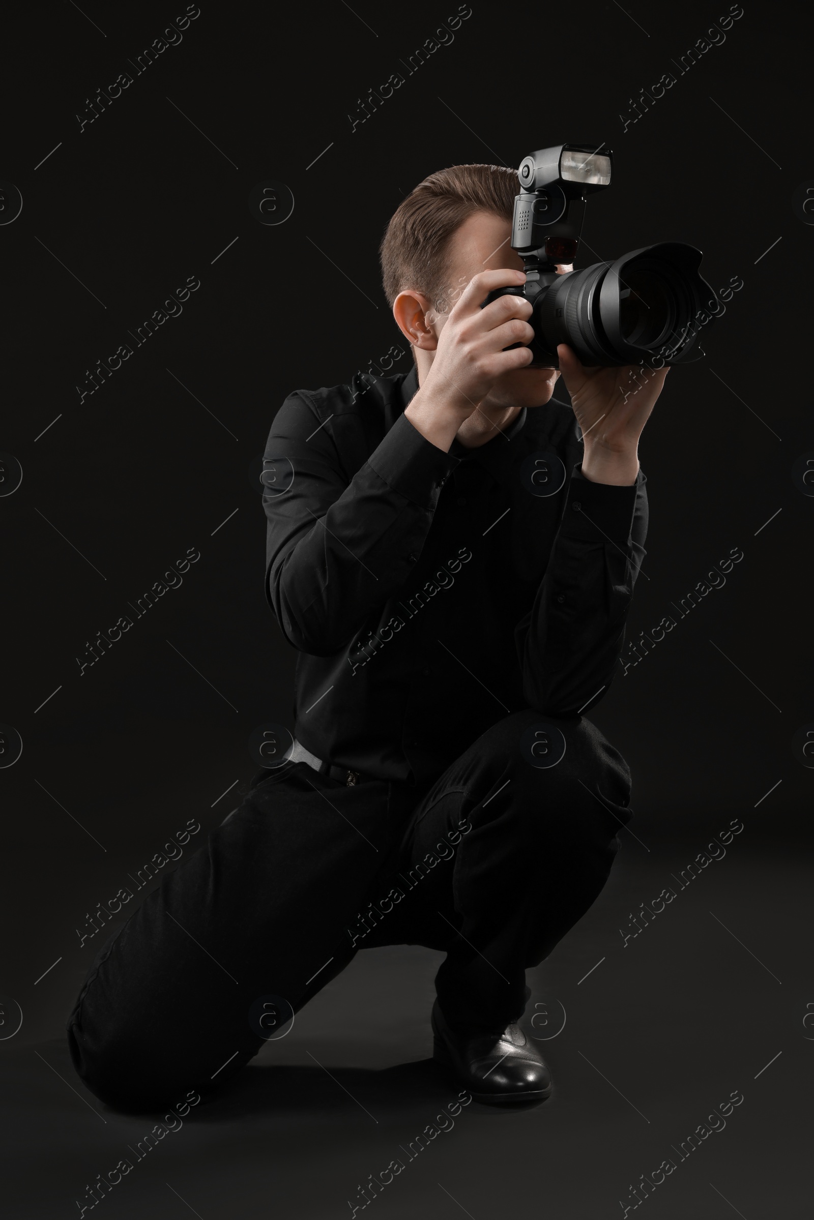 Photo of Professional photographer taking picture on black background