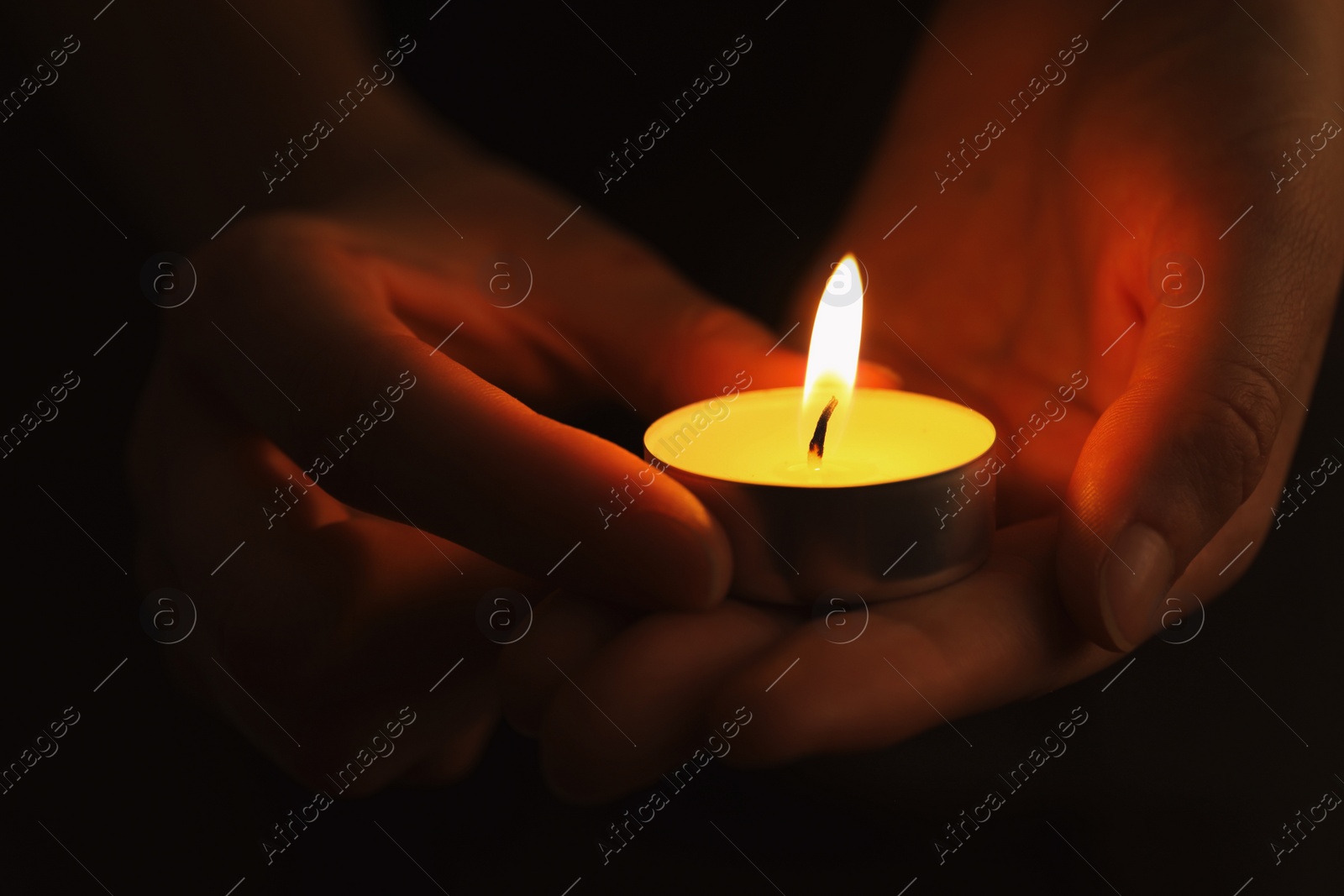 Photo of Woman with burning candle in darkness, closeup. Memory day