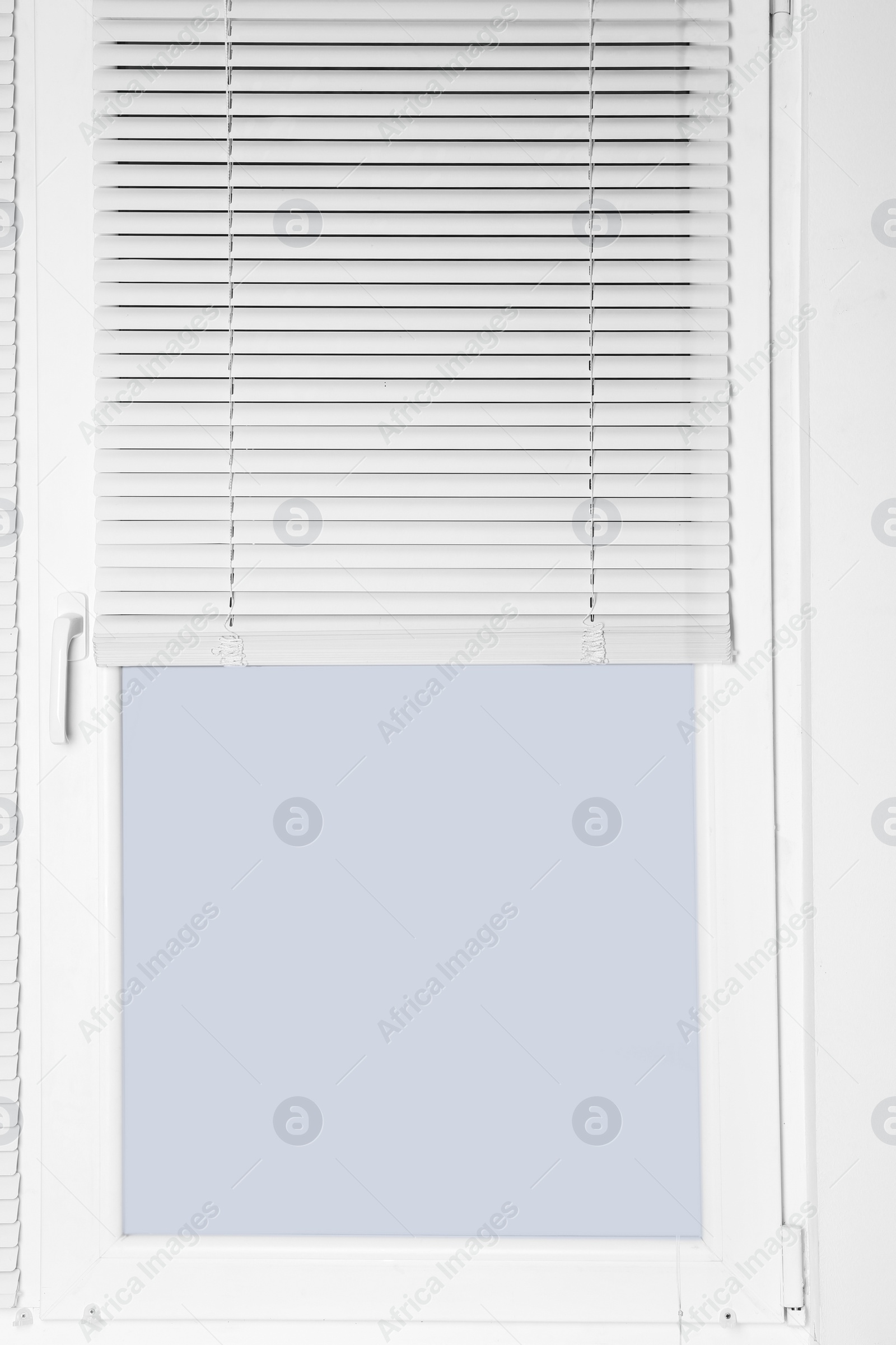 Photo of Modern window with half-closed stylish white blinds