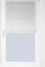 Photo of Modern window with half-closed stylish white blinds