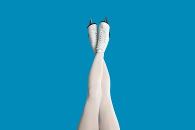 Photo of Woman in elegant white ice skates on light blue background, closeup of legs