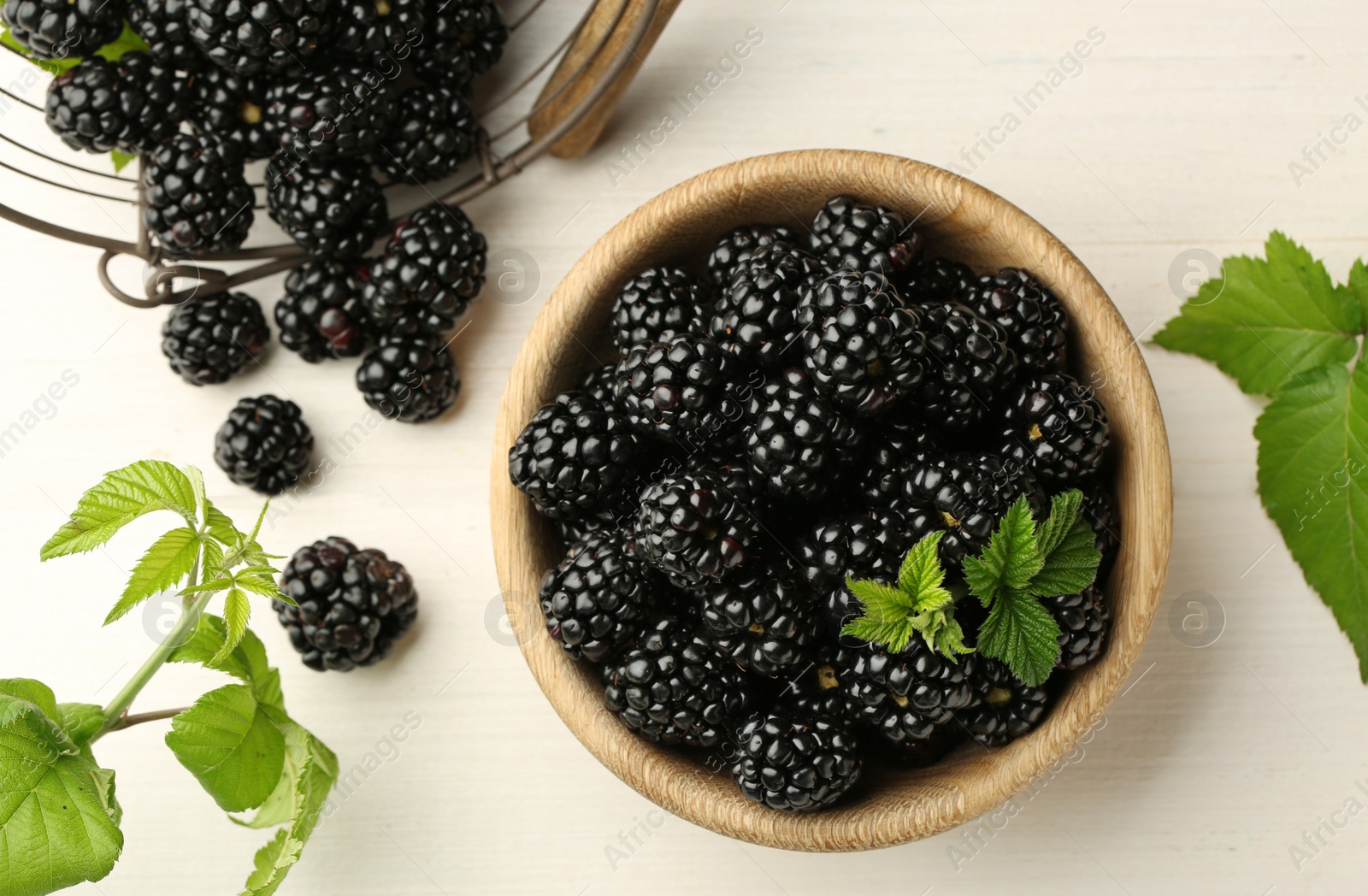Photo of Fresh ripe blackberries on white wooden table, flat lay