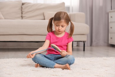 Photo of Cute little girl playing with wooden lacing toy indoors