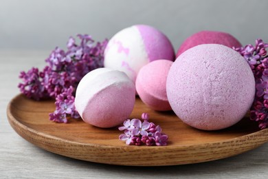 Photo of Fragrant bath bombs and lilac flowers on wooden table, closeup