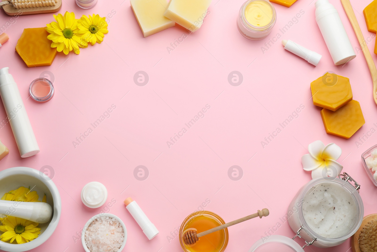 Photo of Frame made of beeswax and cosmetic products on pink background, flat lay. Space for text