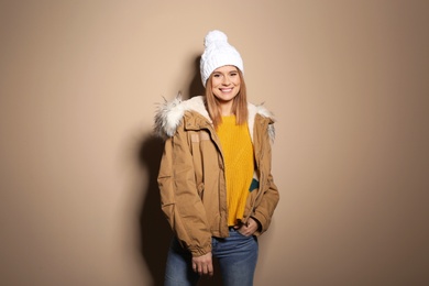 Young woman wearing warm clothes on color background. Ready for winter vacation