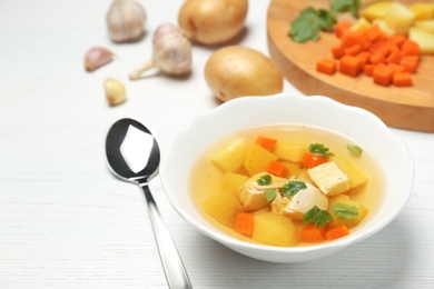 Dish with fresh homemade chicken soup on wooden table, space for text