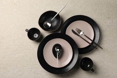 Photo of Stylish table setting. Dishes, cutlery and cups on light surface, flat lay