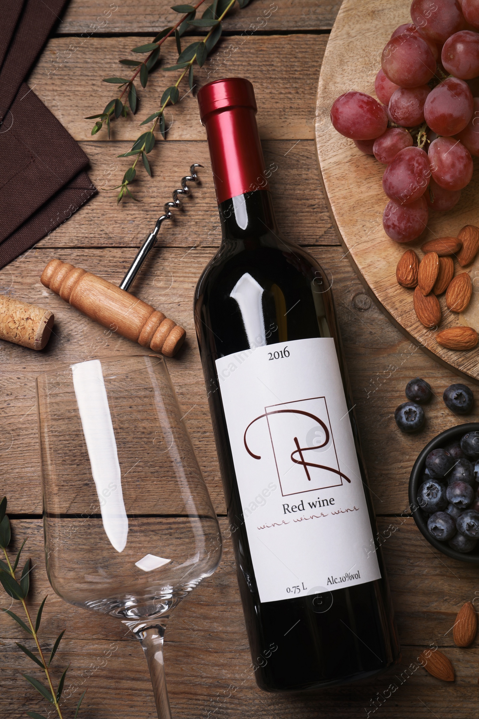 Photo of Bottle of red wine with glass and appetizers on wooden table, flat lay