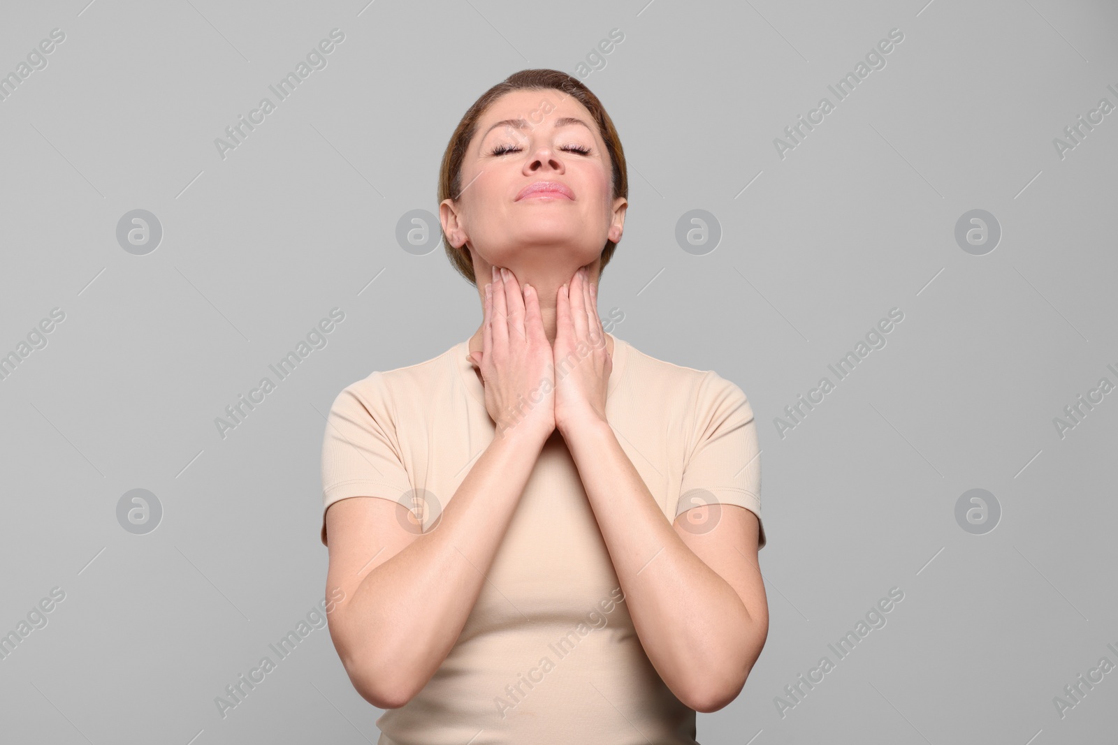 Photo of Woman suffering from sore throat on light grey background