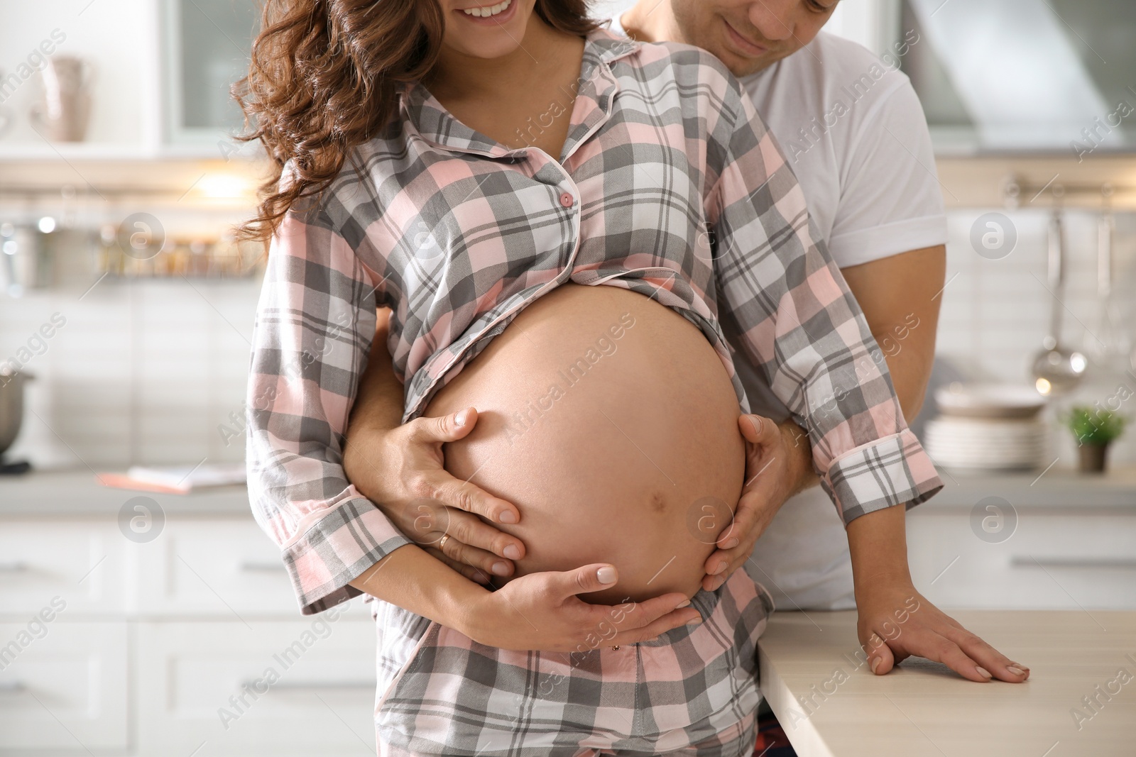 Photo of Pregnant woman with her husband in kitchen. Happy young family