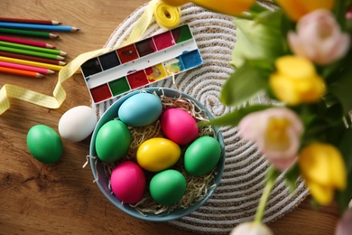 Photo of Flat lay composition with bright painted Easter eggs on wooden table