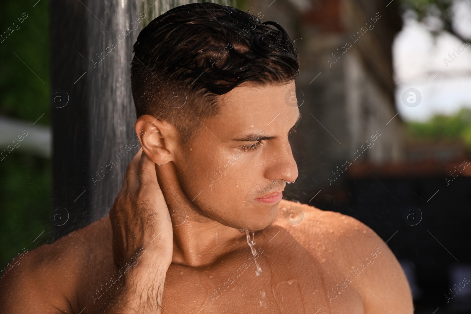 Photo of Man washing hair in outdoor shower on summer day, closeup