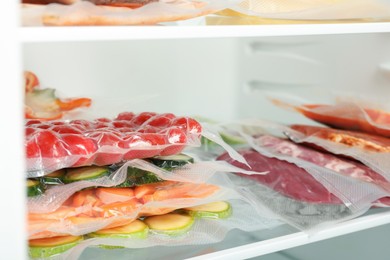Vacuum bags with different products in fridge, space for text. Food storage