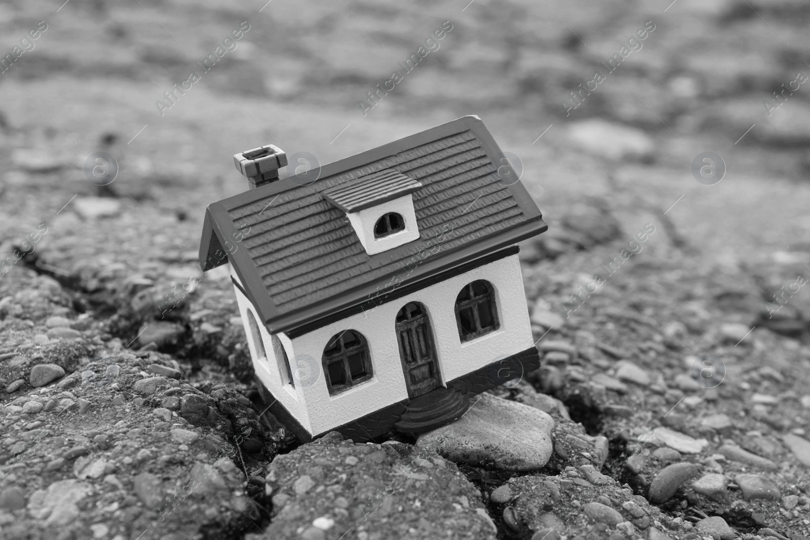 Photo of House model in cracked asphalt. Earthquake disaster