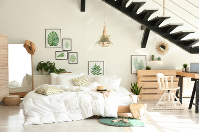 Elegant interior of bedroom with workplace under stairs