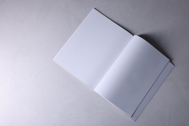 Open notebook with blank paper sheets on grey textured background, top view. Mockup for design