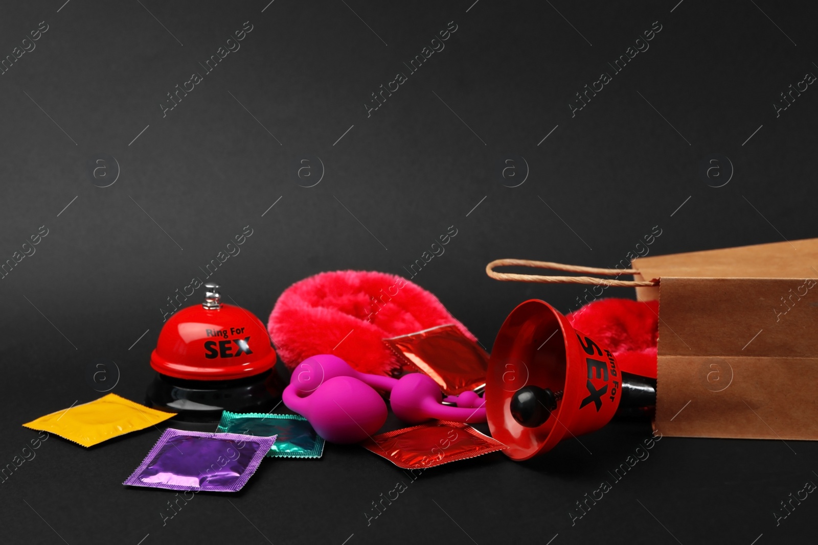 Photo of Shopping bag and different sex toys on black background