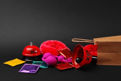 Photo of Shopping bag and different sex toys on black background