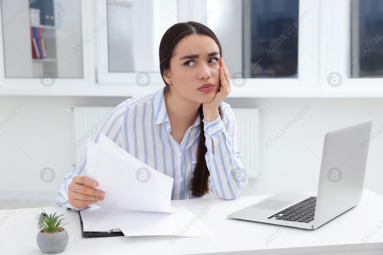 Photo of Unhappy young female intern at table in office