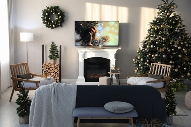 Photo of Modern TV set on light wall in room decorated for Christmas