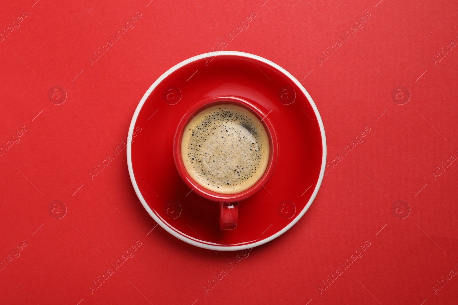 Photo of Tasty coffee in cup on red background, top view