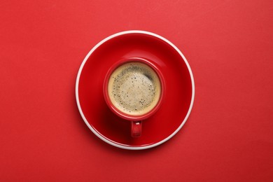 Photo of Tasty coffee in cup on red background, top view