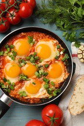 Photo of Delicious Shakshuka in frying pan served on light blue wooden table, flat lay