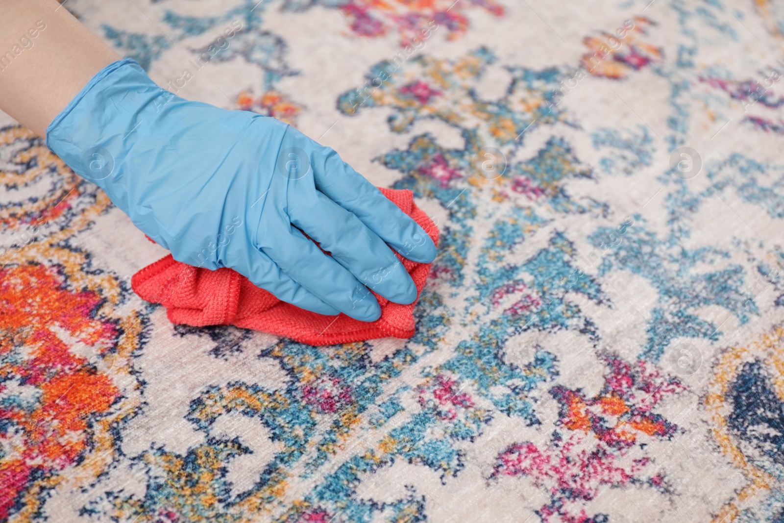 Photo of Woman in rubber gloves cleaning carpet with rag, closeup. Space for text