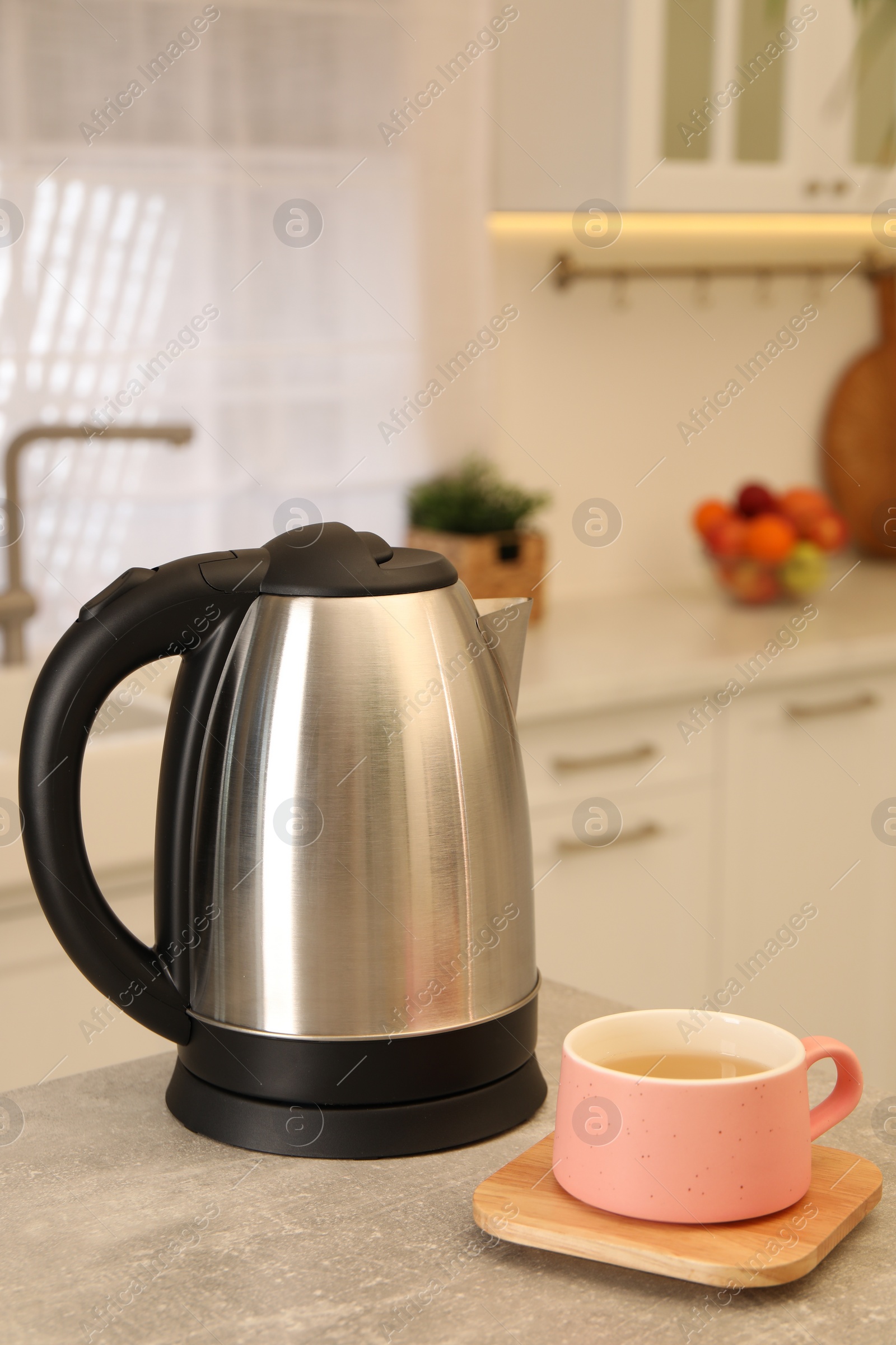 Photo of Electric kettle and cup on table in kitchen