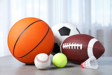 Set of different sport balls and shuttlecock on light grey table