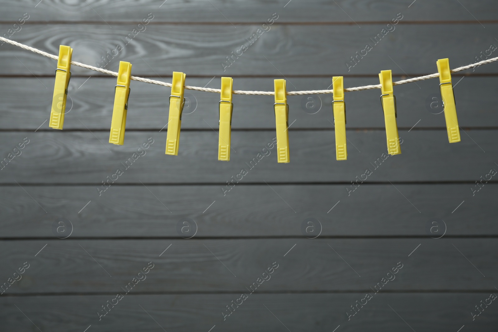 Photo of Colorful plastic clothespins on rope against wooden background. Space for text